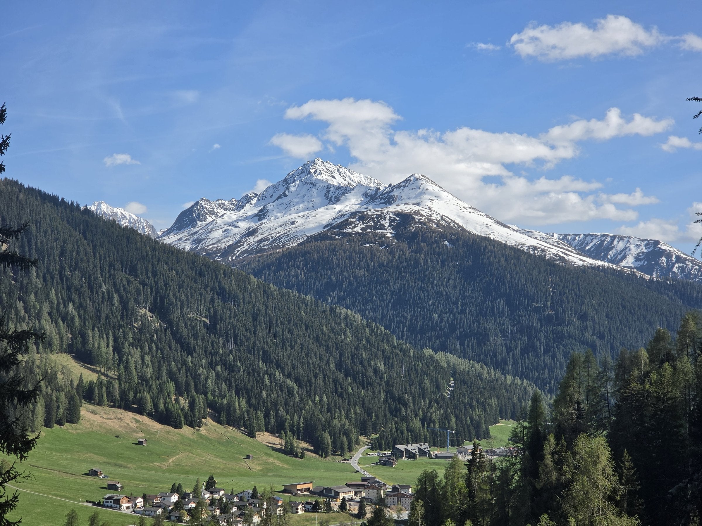 Green alpine valley with village and snow-capped peak in Switzerland